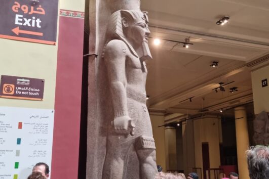 Touristen bestaunen eine antike Statue im Ägyptischen Museum in Kairo während eines Marsa Alam Pyramiden Ausflugs.