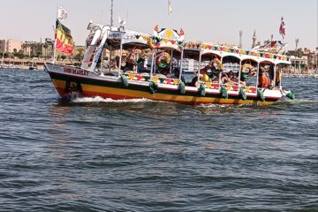Touristen auf einem Boot auf dem Nil während ihres Hurghada Ausflug nach Luxor – im Hintergrund die Tempel von Luxor.