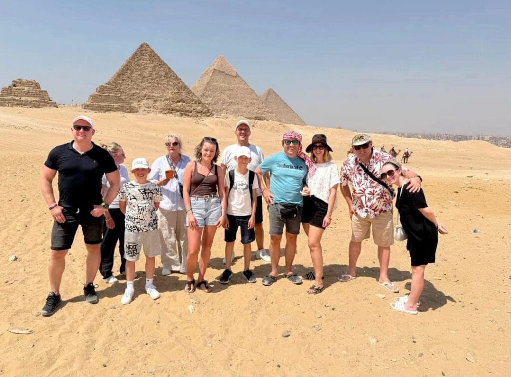 Kairo Pyramiden besichtigen: Der vollständige Guide für Ihren Besuch 3 Fröhliche Reisegruppe vor den drei Pyramiden von Gizeh bei einem Besuch der Kairo Pyramiden.