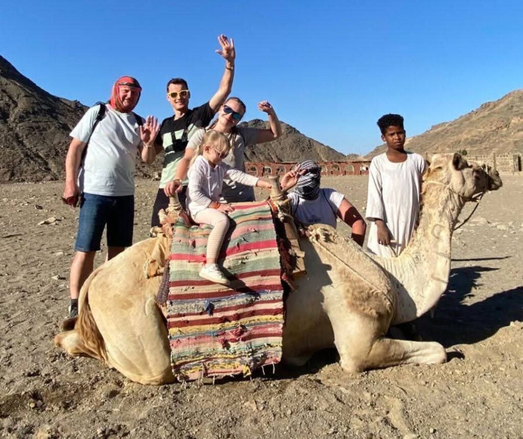 Ein schünes Foto zeigt ein Kind mit seiner Familie auf ein Kamel bei Hurghada Ausflüge mit Kindern