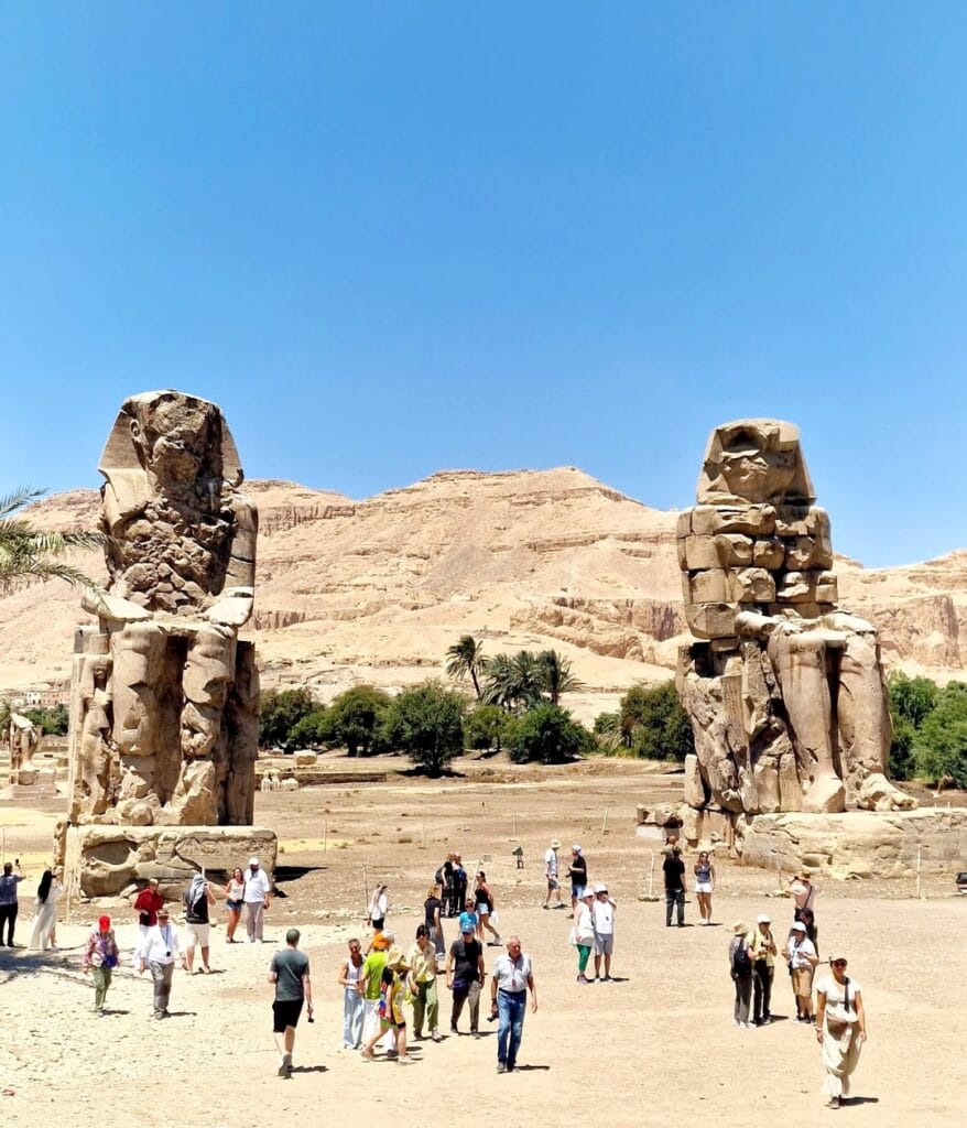 Die monumentalen Memnonkolosse in Luxor während eines Ausflugs auf der Westbank unter blauem Himmel.