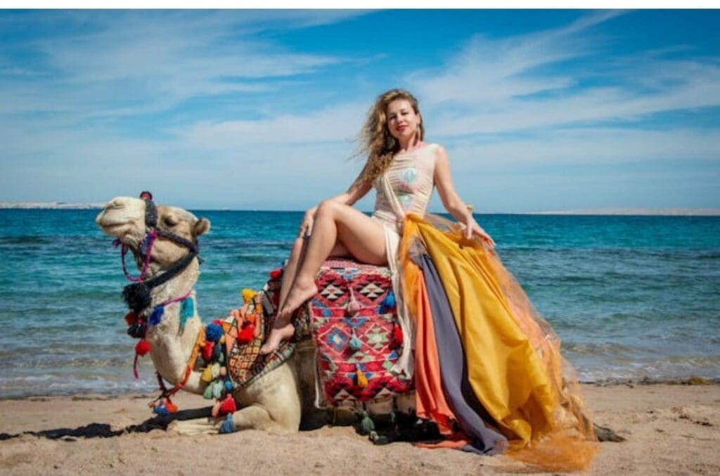 Frau auf einem Kamel am Strand von Marsa Alam im Dezember bei sonnigem Wetter und ruhigem Meer