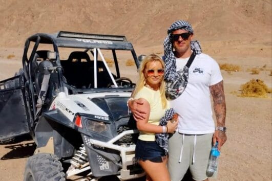 Ein Paar steht lächelnd neben einem modernen Sandbuggy während Ausflug Safari Marsa Alam mit dem Buggy.
