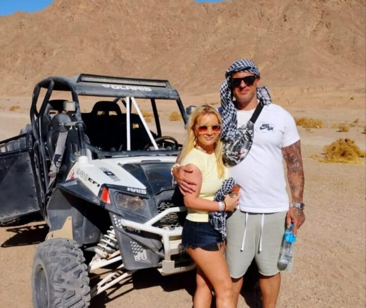 Ein Paar steht lächelnd neben einem modernen Sandbuggy während Ausflug Safari Marsa Alam mit dem Buggy.